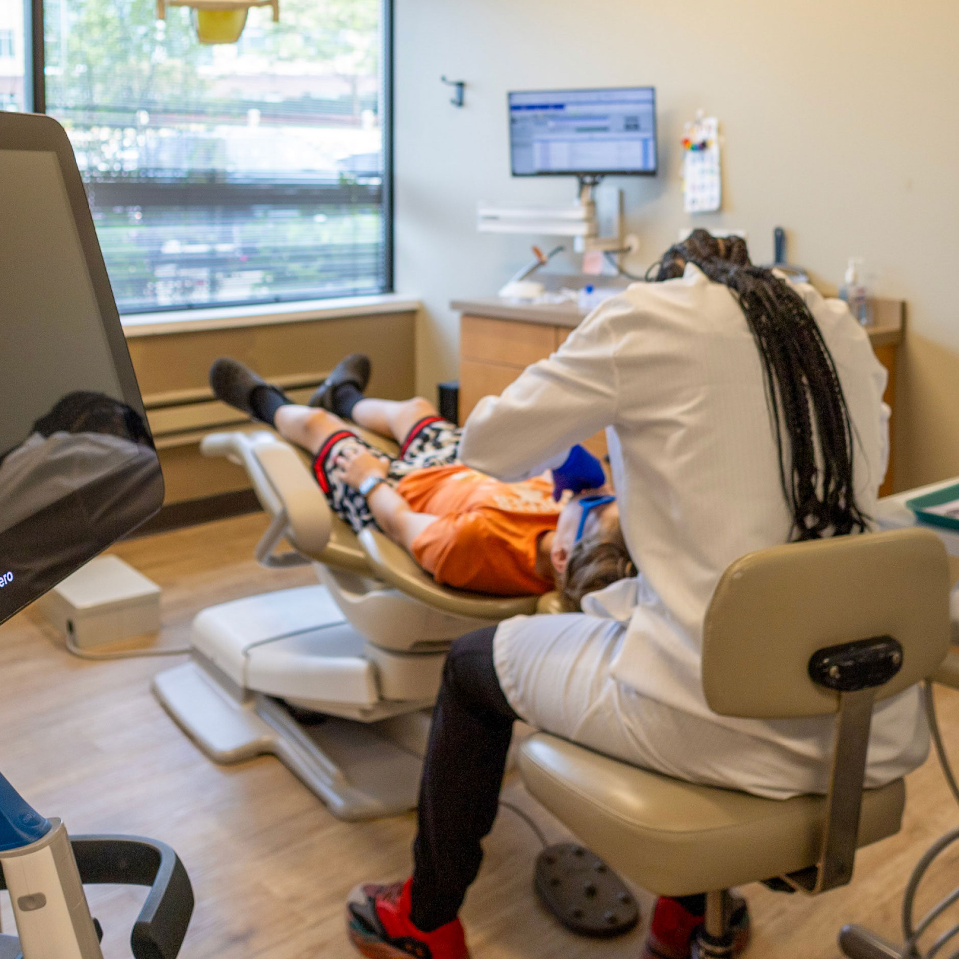 assistant performing dental exam on young patient