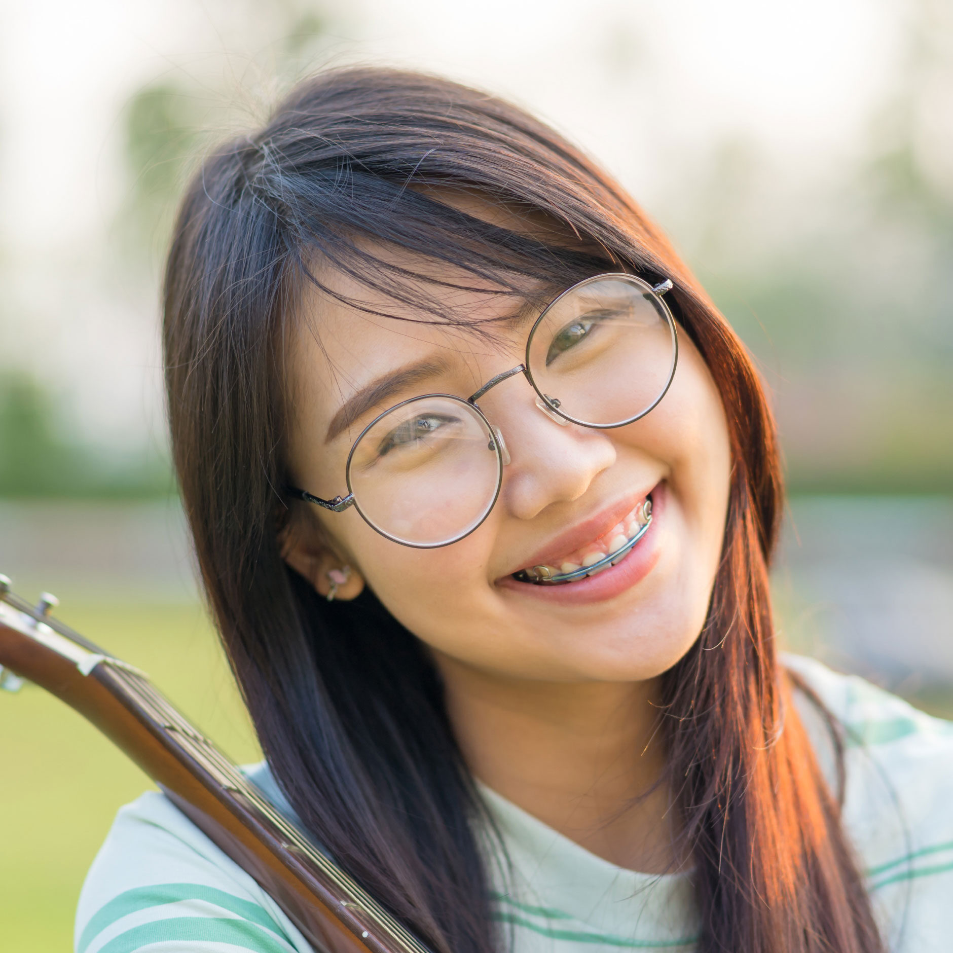 asian girl with retainer smiling at camera in park like setting